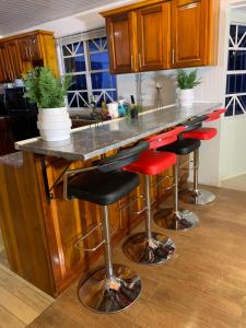 a kitchen with a counter with red stools at 1 Bed Villa - Sleeps 4 - Pool - Parking - Wifi in Georgetown