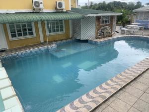 a swimming pool with blue water in front of a house at Cozy first floor accommodation 4 guests 1 bedroom in Georgetown