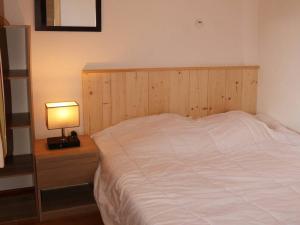 1 cama con cabecero de madera y mesita de noche con lámpara en Appartement Les Orres, 1 pièce, 6 personnes - FR-1-322-95 en Les Orres