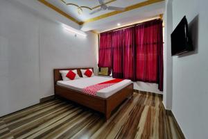 Un dormitorio con una cama y una ventana con cortinas rojas. en Super Hotel O Mahal Inn, en Patna