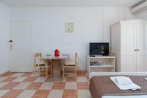 a room with a table and a bed and a television at Apartments Family Gligora in Mandre