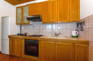 a kitchen with wooden cabinets and a sink and a refrigerator at Apartment Jordan in Duće