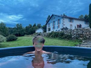 un hombre en una bañera con una casa en el fondo en La Belle Des Vosges en Le Tholy