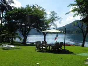 ein Tisch mit Stühlen und ein Regenschirm neben einem See in der Unterkunft Villa Santa Maria in Santa María del Oro