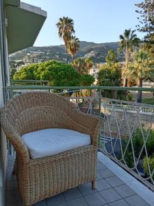 une chaise en osier assise sur un balcon avec des palmiers dans l'établissement appartamento incantevole a Ospedaletti(Sanremo), à Ospedaletti