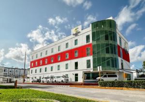 un edificio rosso bianco e verde con auto parcheggiate fuori di Comfort Inn Cancún Aeropuerto a Cancún