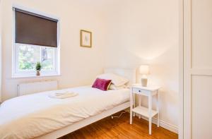 a white bedroom with a bed and a window at Modern 2 Bedroom Apartment in Romford