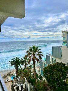 a view of the ocean with palm trees and buildings at Clifton Beach Apartment in Cape Town