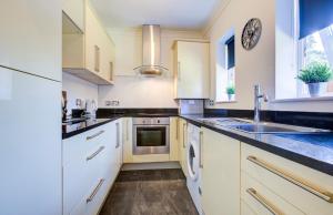 a kitchen with white cabinets and a sink at Modern 2 Bedroom Apartment in Romford