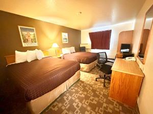 Cette chambre comprend deux lits et un bureau. dans l'établissement FairBridge Inn, Suites & Conference Center – Missoula, à Missoula