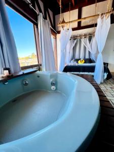 a large bath tub in a room with a window at Pousada Sonho do Vale in Praia do Rosa