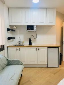 a kitchen with white cabinets and a sink and a couch at Plaza de España independent house in Barcelona