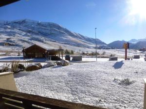 un patio cubierto de nieve con un edificio y una montaña en Appartement Huez, 1 pièce, 4 personnes - FR-1-405-45 en L'Alpe-d'Huez