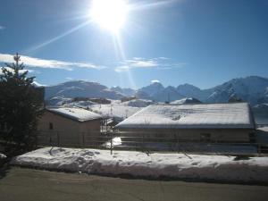 um edifício coberto de neve com o sol no céu em Appartement Huez, 1 pièce, 4 personnes - FR-1-405-35 em Alpe-d'Huez