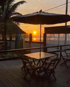 a table and chairs with an umbrella on a deck at Pousada Kai in Itanhaém