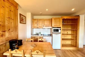 eine Küche mit Holzschränken und einem Holztisch in der Unterkunft Cosy Chalet with Terrace in Combloux