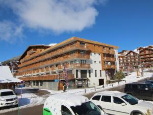 ein großes Gebäude mit Autos auf einem Parkplatz in der Unterkunft Appartement Huez, 1 pièce, 4 personnes - FR-1-405-19 in L'Alpe-d'Huez