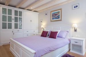 a white bedroom with a large bed with purple pillows at Studio Apartments Sonatina in Dubrovnik +65 photos