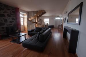 uma sala de estar com um sofá preto e uma escada em Pico da Saudade em Prainha de Baixo