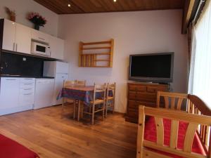 a kitchen with a table and a tv on a wall at Appartement Huez, 1 pièce, 4 personnes - FR-1-405-117 in L'Alpe-d'Huez