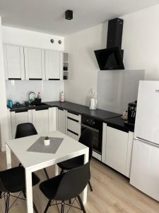Una cocina con una mesa blanca y electrodomésticos negros. en PK Premium Apartments, en Bolesławiec 3 fotos más