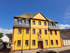 a yellow house with a horse on the front of it at Hotel zum Hirsch in Lucka