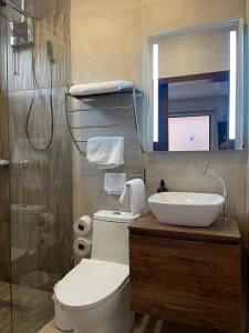 a bathroom with a toilet and a sink and a mirror at Kiran Lodging Guayaquil in Guayaquil