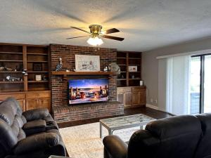 a living room with a couch and a brick fireplace at Nautical Nirvana-Waterfront Joys from Sunrise Paddles to Hot Tub Sunsets in Panama City