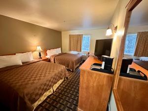 a hotel room with two beds and a flat screen tv at FairBridge Inn & Suites Kellogg in Kellogg