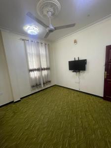 Habitación vacía con ventilador de techo y TV de pantalla plana. en Furaha Suite Apartment, en Mwana Kerekwe