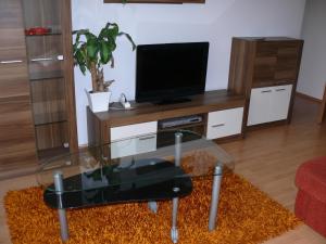 ein Wohnzimmer mit einem Glastisch und einem TV in der Unterkunft Villa Palazzo Apartments in Siófok