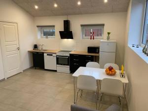 uma cozinha com uma mesa e cadeiras brancas e uma cozinha com um lavatório em Small Rica house in the center in Billund em Billund