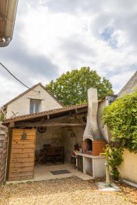 eine Terrasse mit einem Backofen im Freien in einem Haus in der Unterkunft La maisonnette du Vivier in Couffy