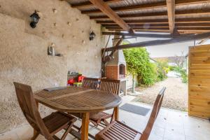 einen Holztisch und Stühle auf einer Terrasse in der Unterkunft La maisonnette du Vivier in Couffy