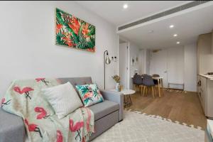 uma sala de estar com um sofá cinzento e uma cozinha em Modern 1 BR Apt on Southbank #Australia108#AU2117 em Melbourne