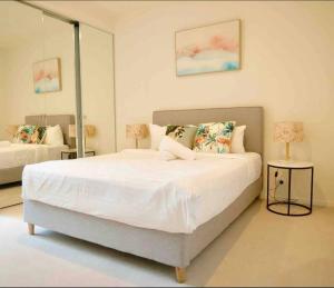 um quarto com uma grande cama branca e um espelho em Modern 1 BR Apt on Southbank #Australia108#AU2117 em Melbourne
