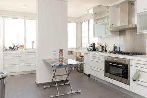 uma cozinha com armários brancos e uma mesa de vidro em Loft With a View 24 7 Electricity em Beirute