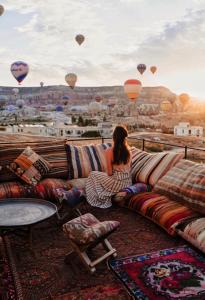 a woman sitting on a couch looking at hot air balloons at Perla Cappadocia in Goreme