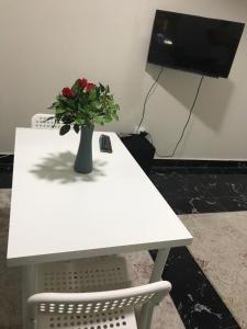Comfort suite في القاهرة: طاولة بيضاء مع مزهرية عليها زهور حمراء