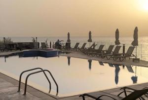 a swimming pool with chairs and the ocean in the background at Banana Leaf Beachfront Exotic Room in Batroun 