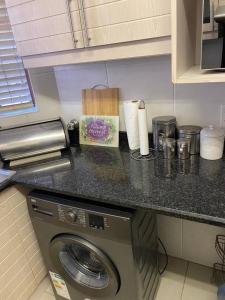 a counter with a washing machine in a kitchen at Off-shore Guest house in Margate