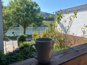 a coffee cup sitting on a table with a view of a river at Ferienhaus Fridolin in Zell an der Mosel