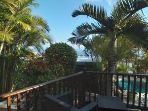 a resort balcony with palm trees and a swimming pool at Studio aux AVIRONS pour 2 personnes, avec piscine in Les Avirons