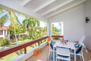 eine Veranda mit einem Tisch und Stühlen auf dem Balkon in der Unterkunft Antigua Village- Villa Lilly 33B in Dickenson Bay