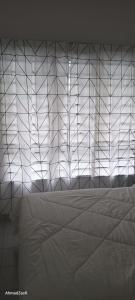 1 dormitorio con cama blanca y pared de cristal en D CAMYLIA PUTRAJAYA HOMESTAY, en Putrajaya
