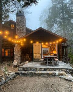 a log cabin with a table and lights on it at Owl Pine Cabin on Strawberry Creek in Idyllwild