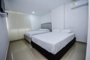 2 camas en una habitación con paredes blancas en APARTAMENTO OCEAN DRIVE 410 CARTAGENA, en Cartagena de Indias