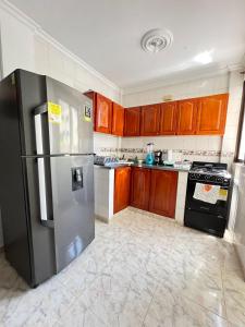 a kitchen with a stainless steel refrigerator and wooden cabinets at Apartamento Vacacional Cartagena Colombia Cerca Aeropuerto y Playa 2 in Cartagena de Indias