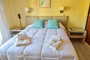 a large white bed with blue pillows on it at Hotel Edith in Villa Gesell