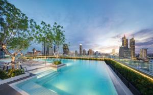 a swimming pool with a city skyline in the background at Grande Centre Point Surawong Bangkok in Bangkok